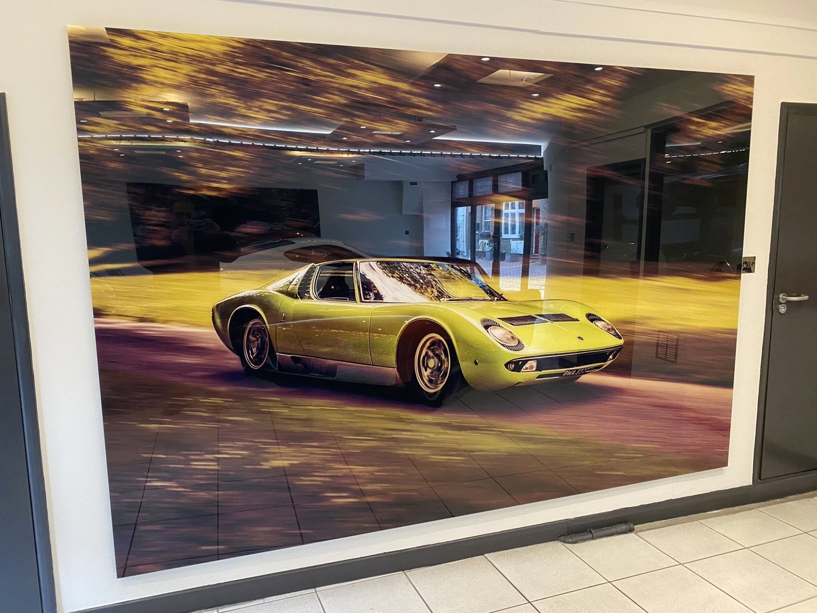 A large Lamborghini Miura print mounted on a showroom wall