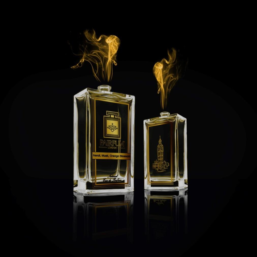 Two Pairfum London perfume bottles with gold smoke rising from them